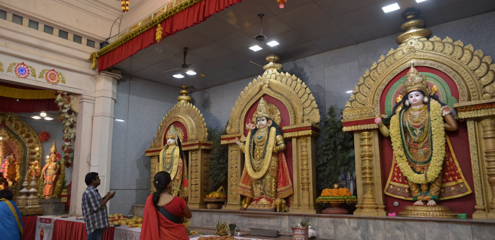 Devotees pray before ornate idols of Navdurga inside a decorated hall, representing the nine devi name sequence of Navratri mata and the worship of maa durga ke 9 roop.
